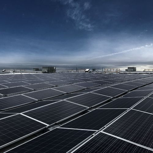 Large-scale rooftop solar panel array with urban landscape background